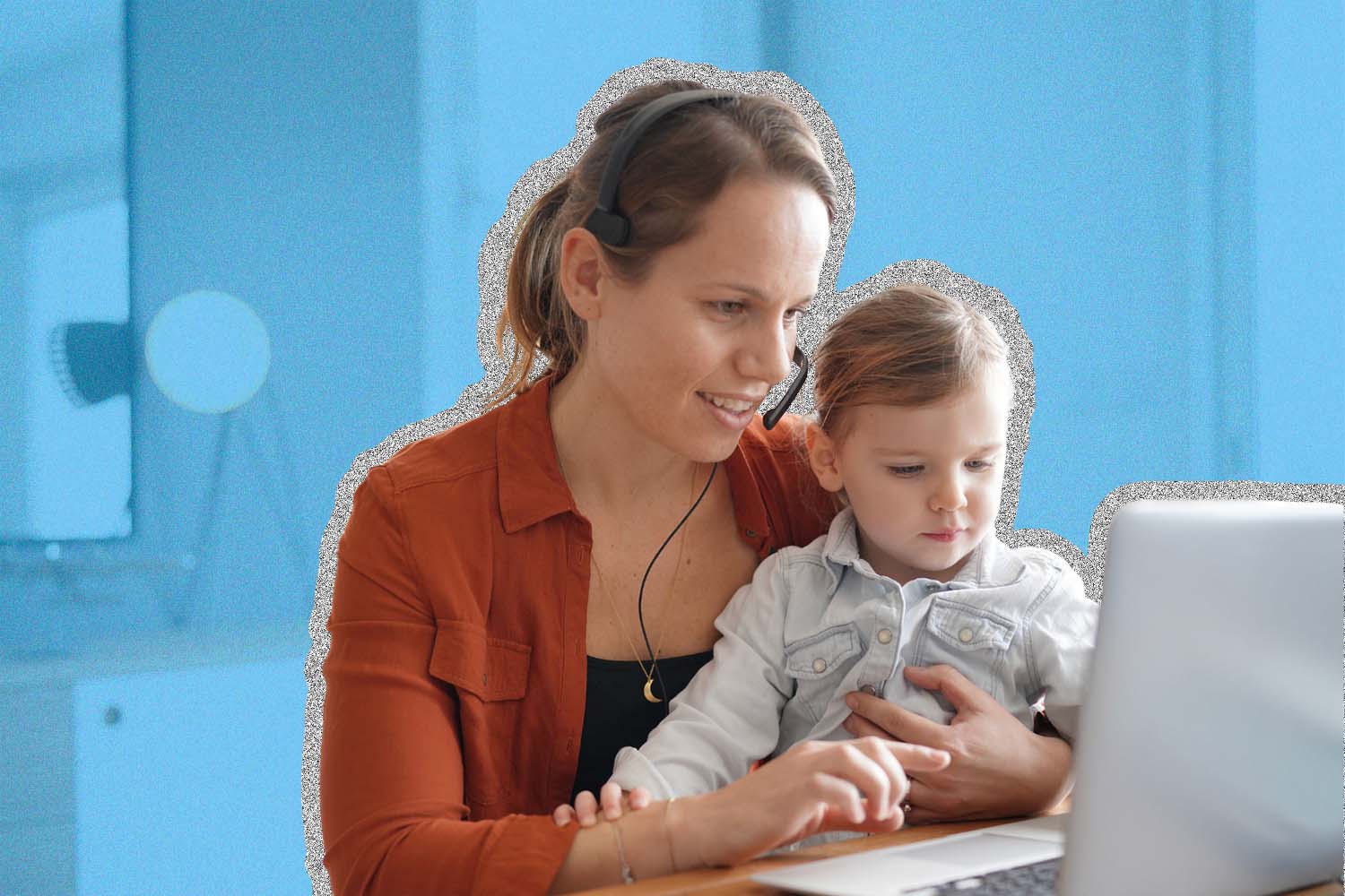 Woman sits at laptop to work while holding a baby