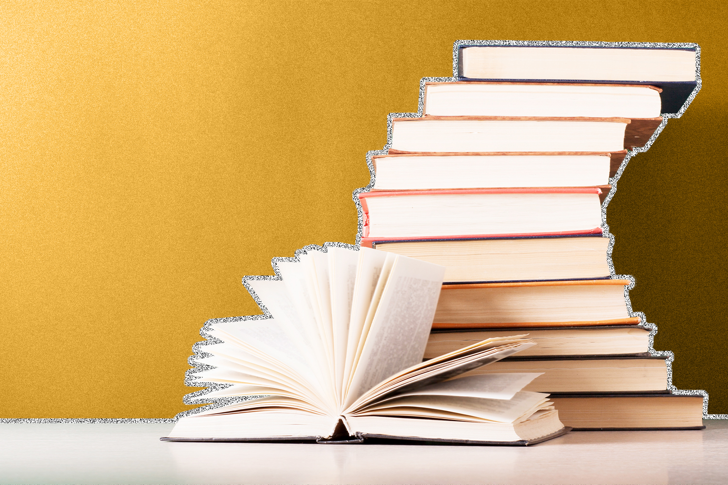 A stack of books on a table, with one book flipped open placed in front of the stack.