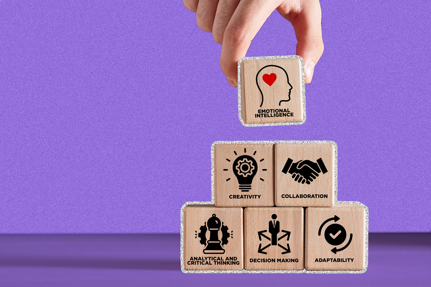 A pyramid of wooden blocks with icons on each to convey learning and professional development on a purple background