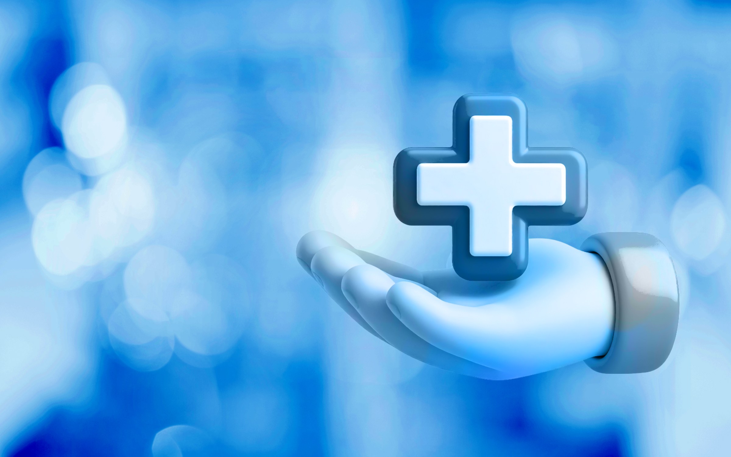 A stylized hand holds a three-dimensional medical cross against a soft blue background with light patterns. The image shows healthcare through symbols of medical assistance and wellness.