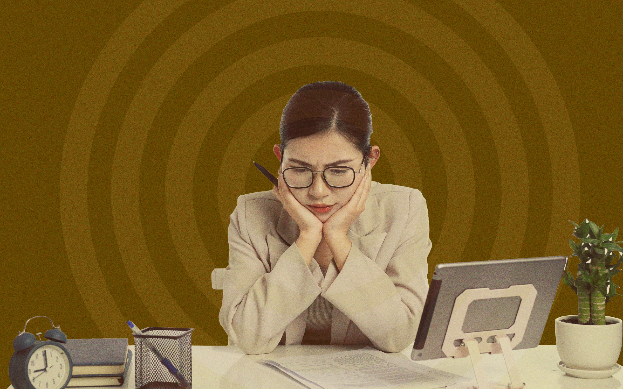 A businesswoman wearing glasses sits at a desk with her face in her hands, looking intently at a tablet and paperwork. An alarm clock, notebooks, pen holder and small potted plant sit nearby, while concentric circles in the background reinforce a sense of complexity and information overload. The image illustrates the challenge marketers face when trying to understand, position and communicate new or complex products and solutions.